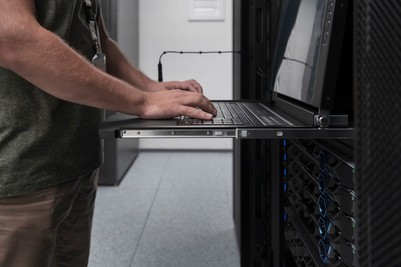 IT-specialist gebruikt zijn computer in een serverruimte om IT-onderhoud uit te voeren